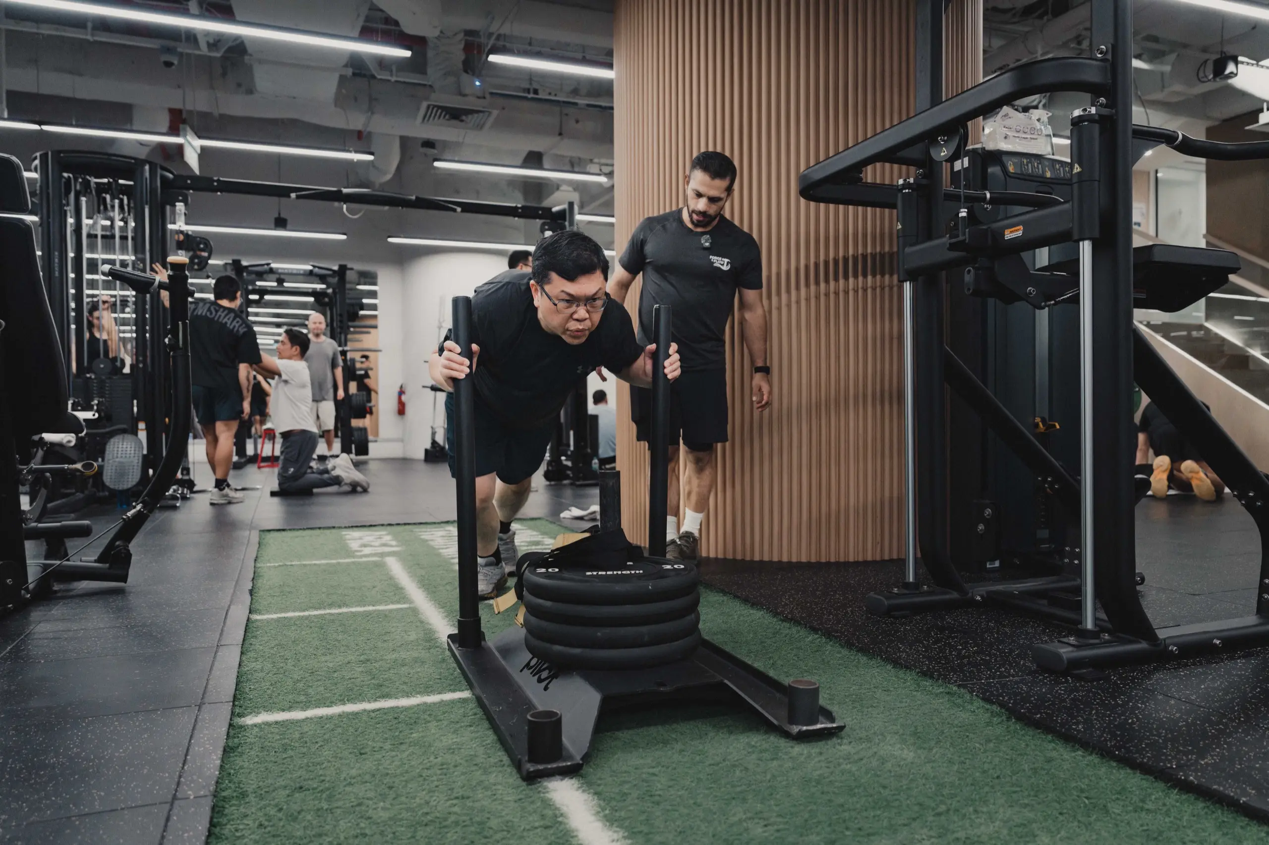 A team member pushing a weighted sled during a coached group session