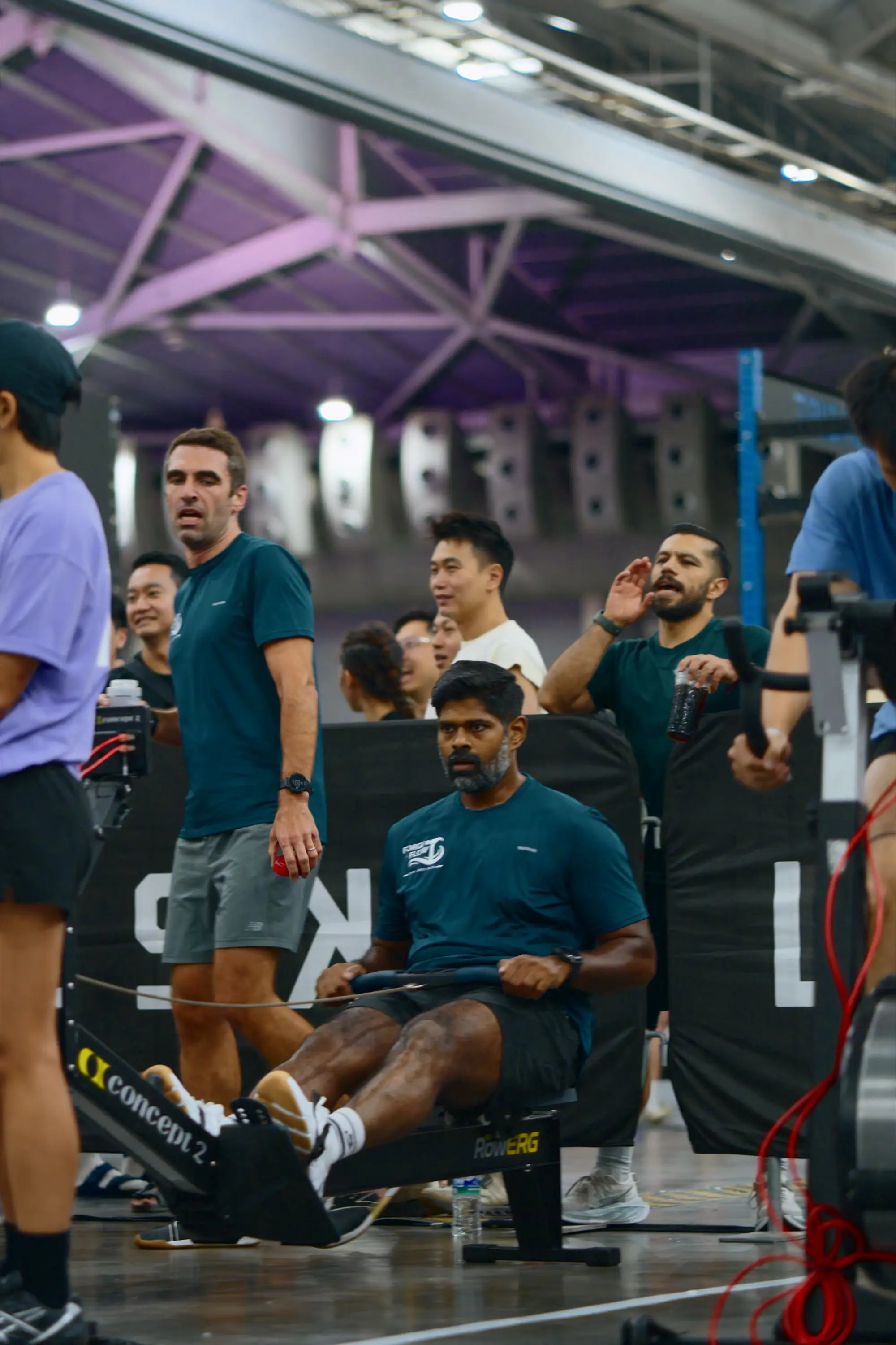 Two Forge & Flow teammates leaning in to encourage a third mid-row at the Turf Games