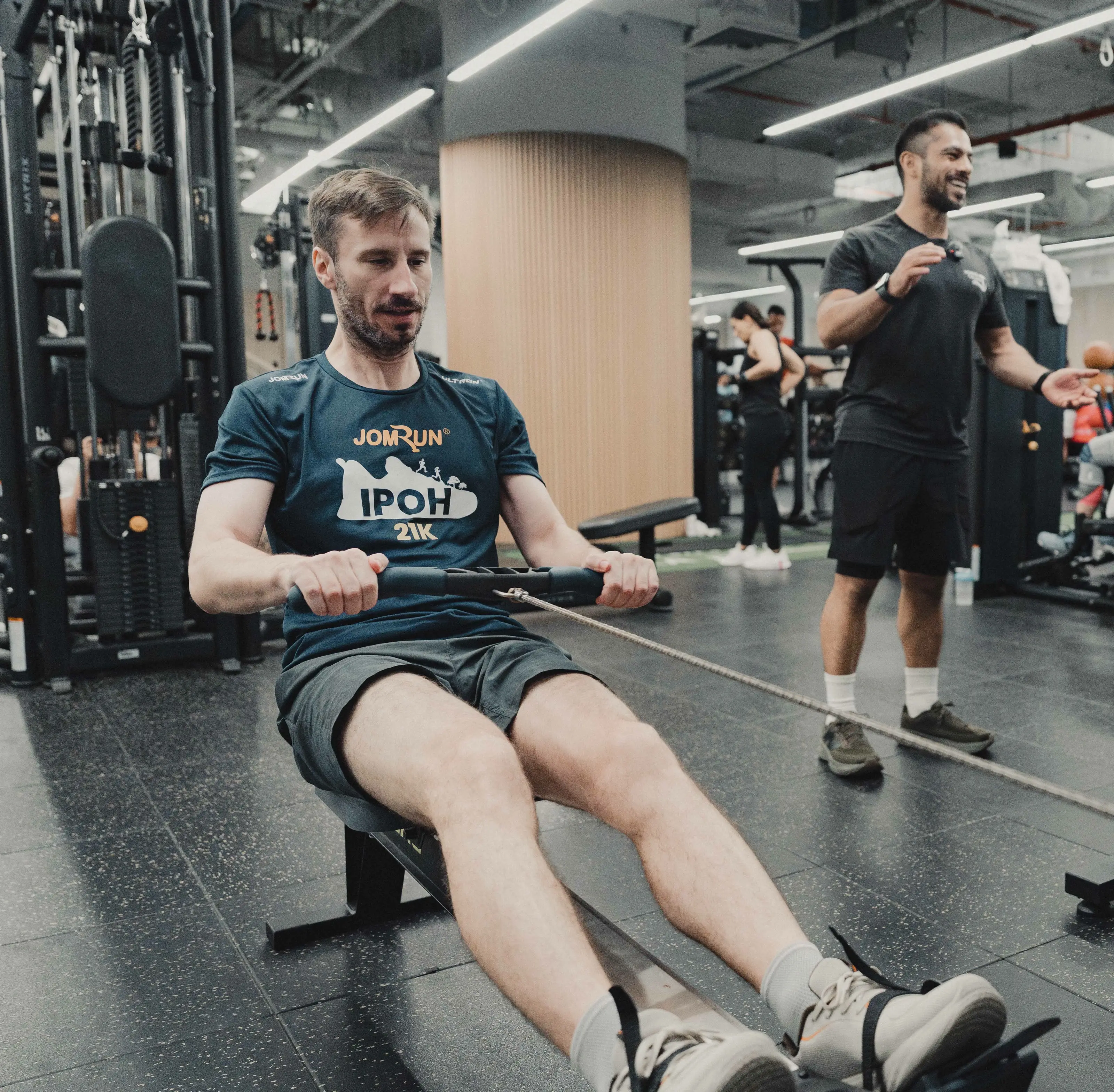 A client rowing during a coached session while Ivan Figueroa coaches from behind