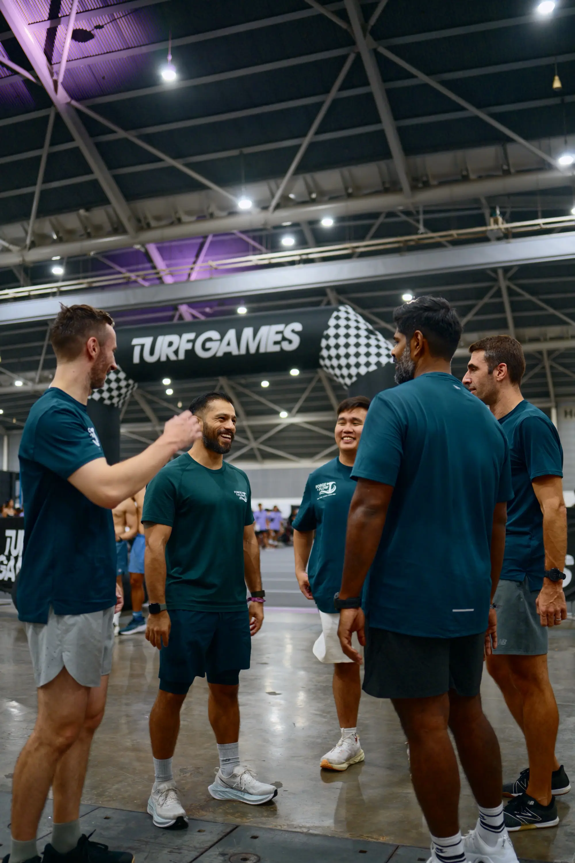 The five-person Forge & Flow team laughing together in a huddle between Turf Games events