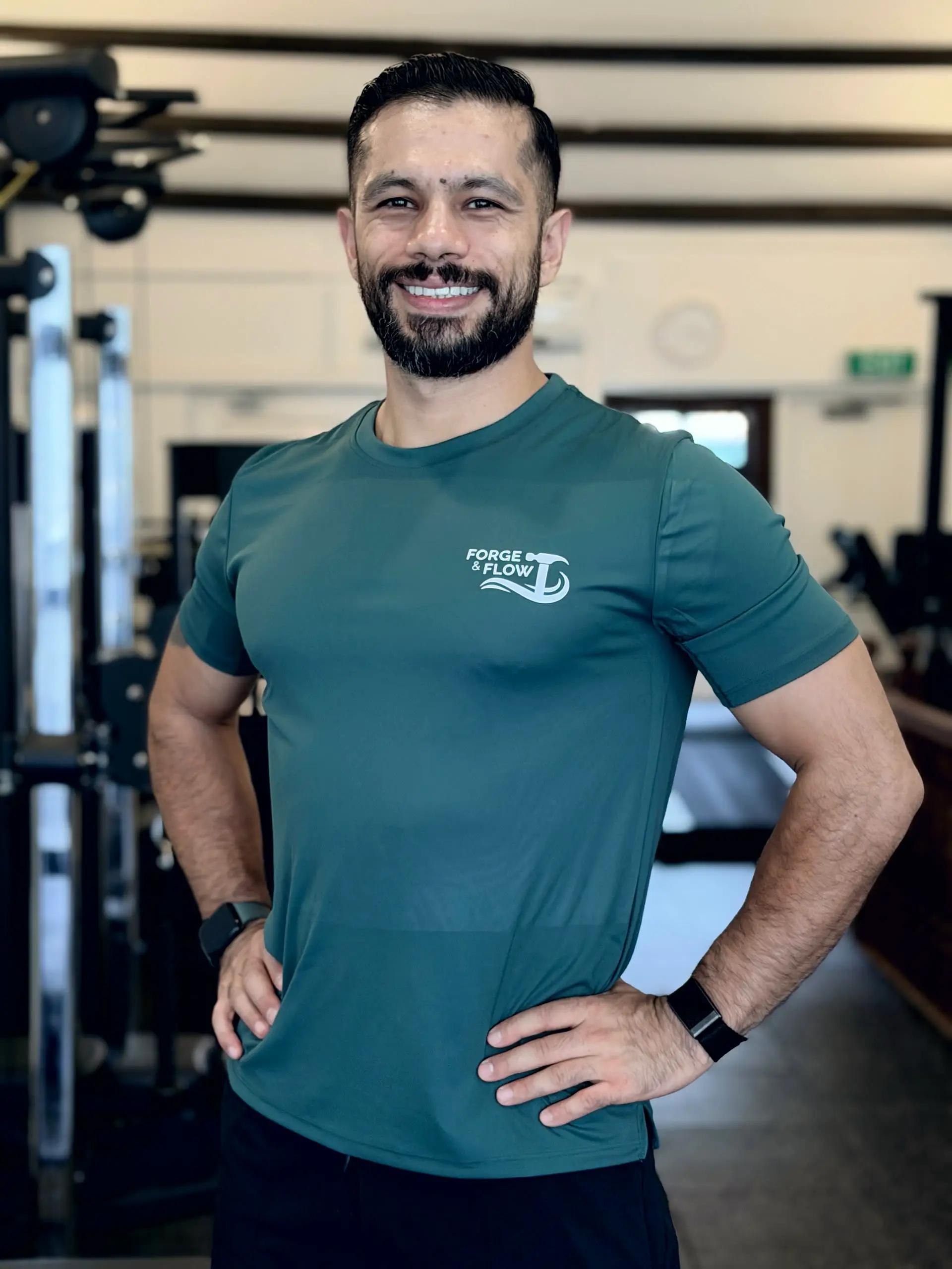 Coach Ivan Figueroa smiling, hands on hips, in the Forge & Flow training space