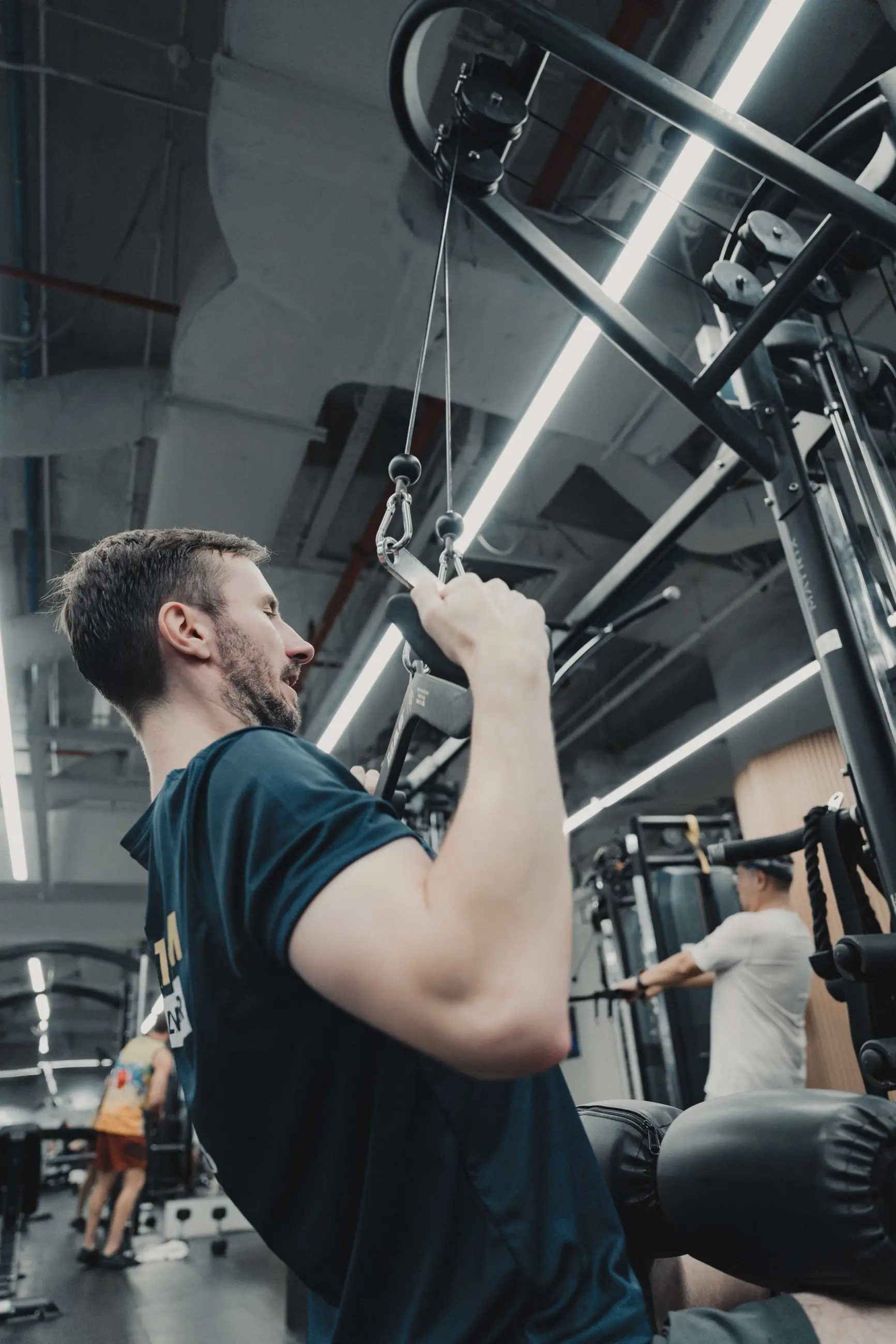 A client in side profile pulling through a lat pulldown at the cable station