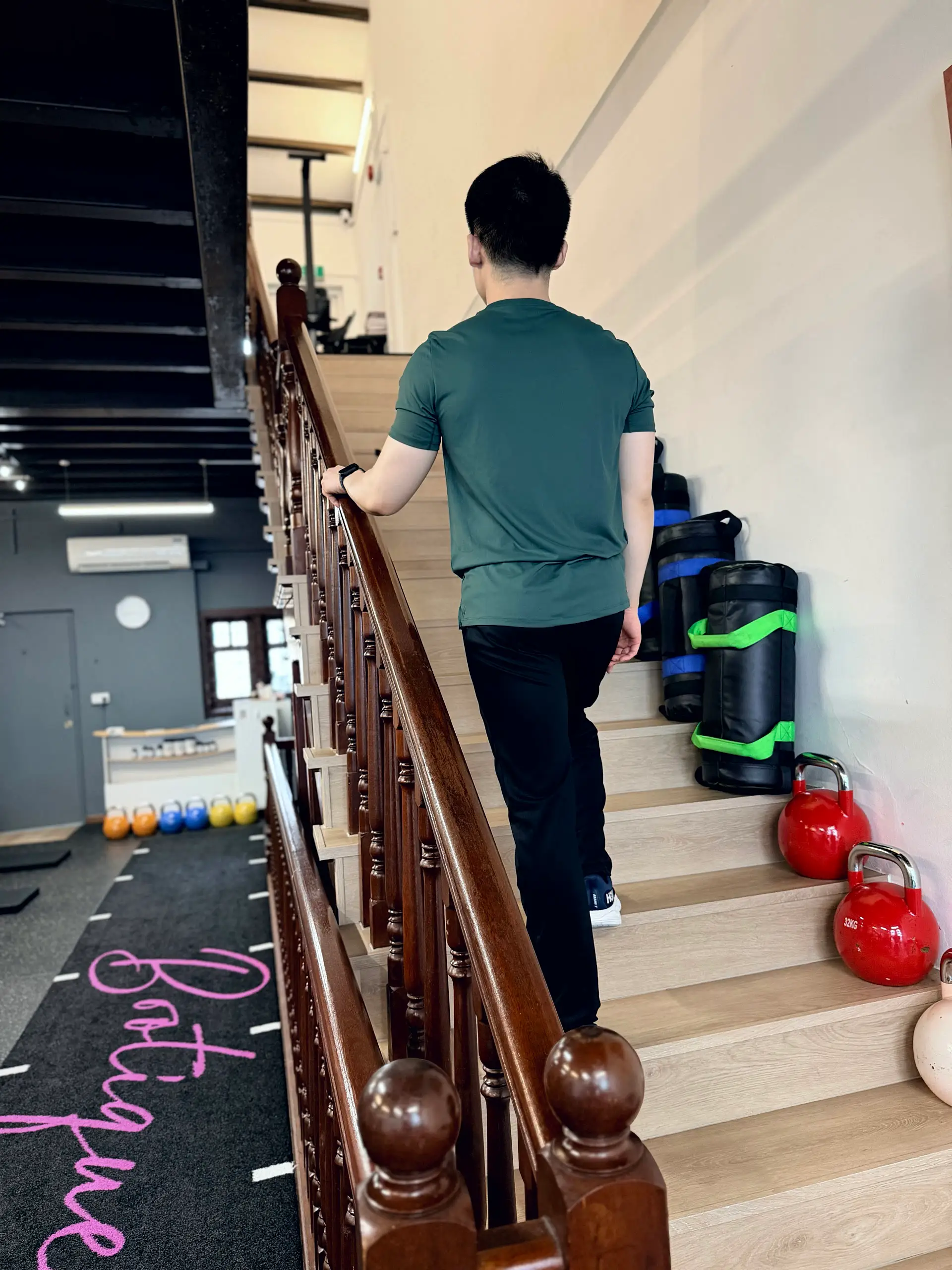Wei Song carrying equipment up the stairs of the Forge & Flow training space